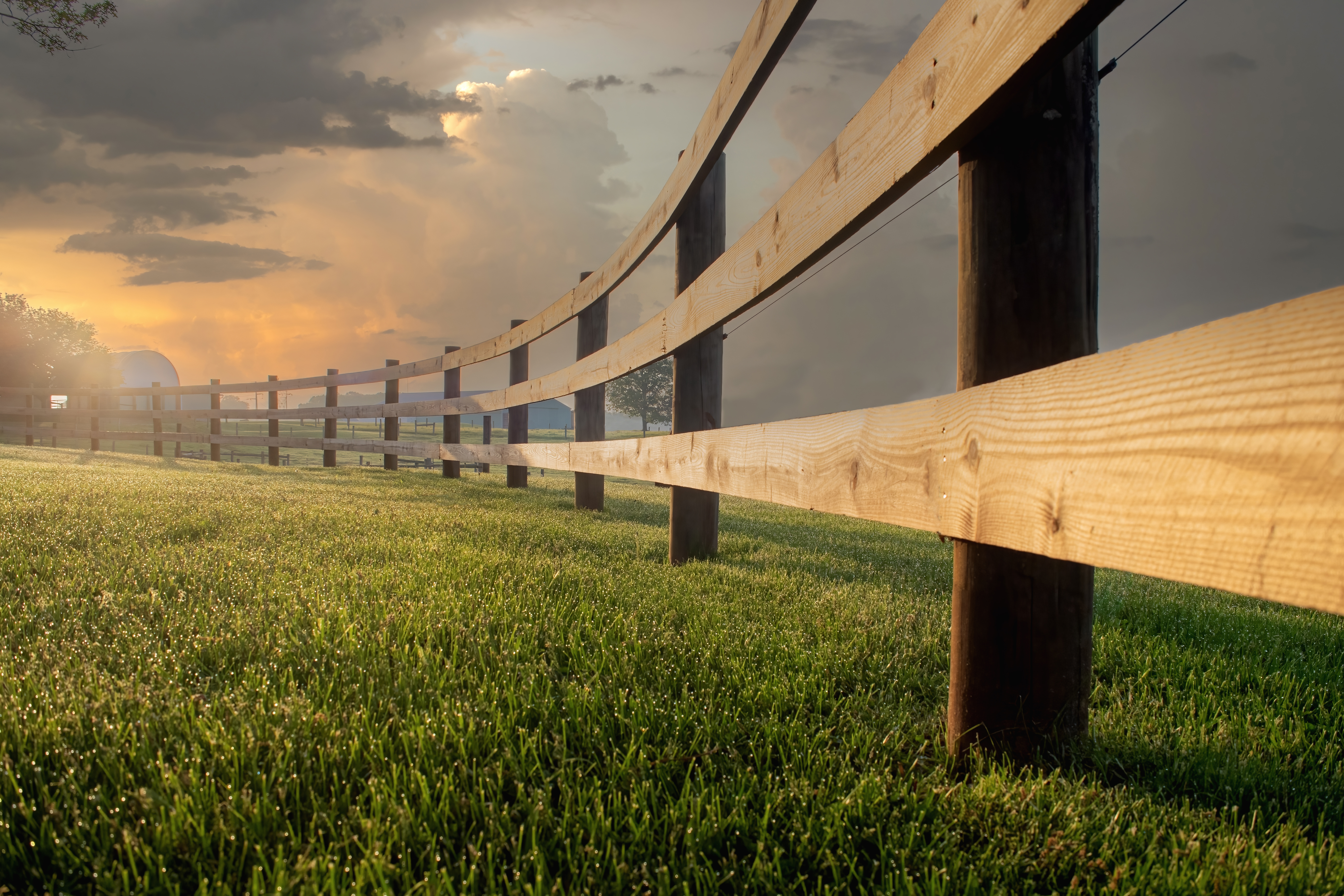 early morning sunrise lights split rail fence on farm